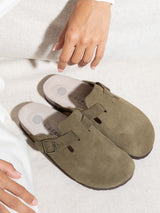 Zueco Genuins Riva de piel serraje color kaki con planta anatómica de corcho y hebilla ajustable metálica, bodegón 
